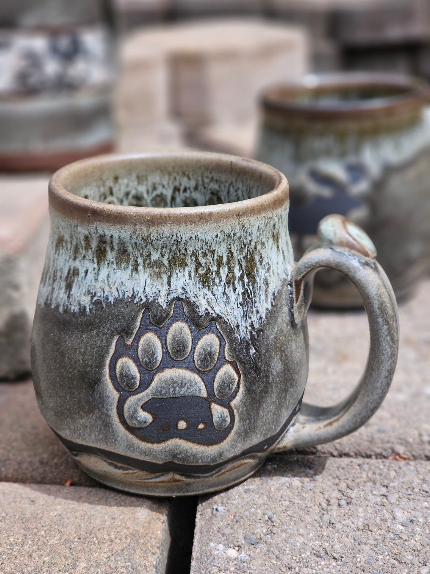 Ceramic mug with paw print design against a stone wall