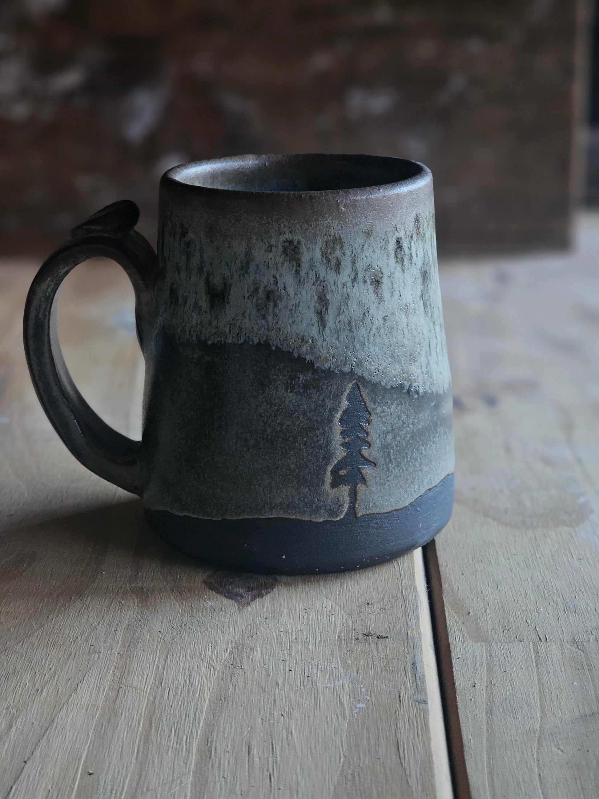 Moody Forest mug featuring resisted pine trees in green and dark gray glaze over black clay- northern Idaho pottery