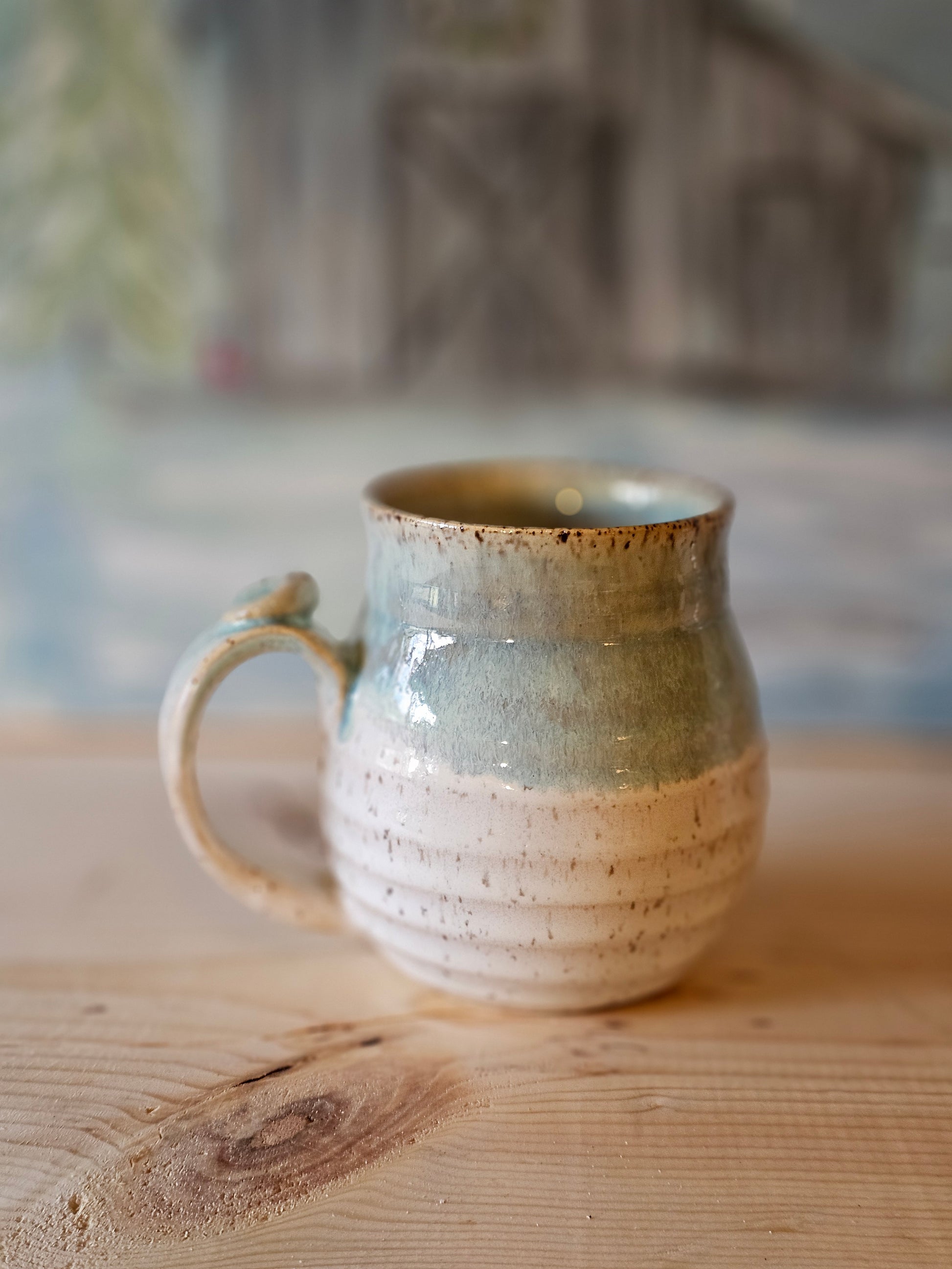 handmade stoneware mug with carved lines and thumb rest - blue rim over white  glaze - handcrafted northern idaho