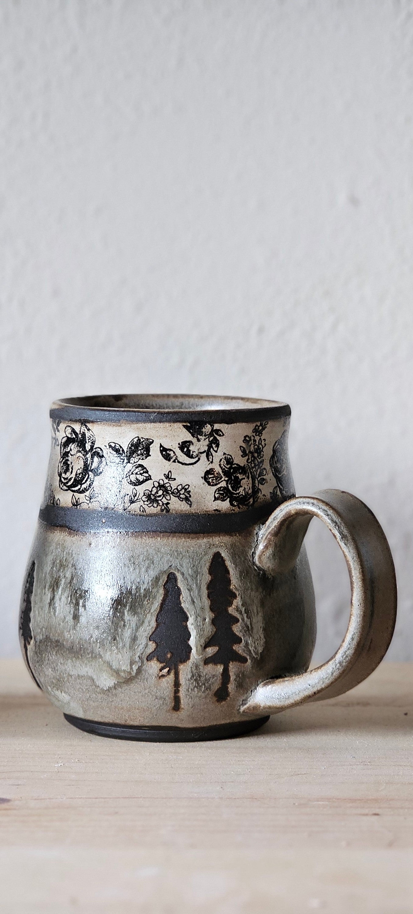 Woodland Heirloom ceramic mug with earthy gray-green glaze, black evergreen trees , nice rounded handle , and vintage inspired band.  