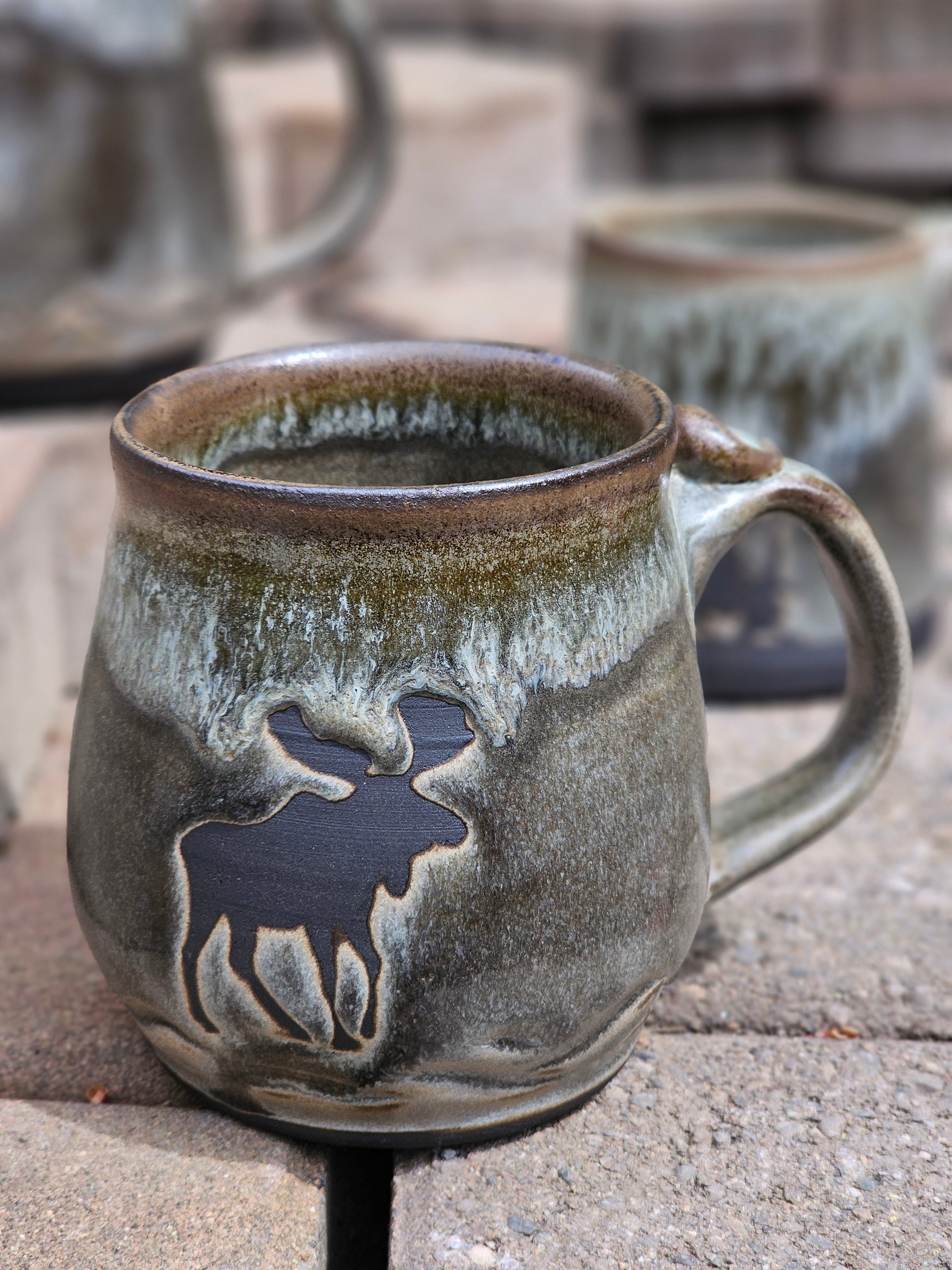 Ceramic mug with moose design on a stone surface