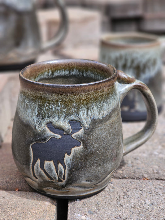 Ceramic mug with moose design on a stone surface