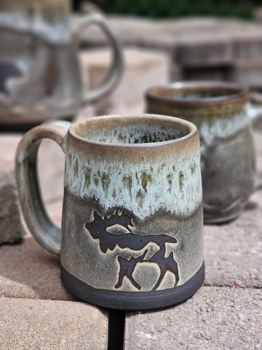 Ceramic mug with moose design on a stone surface